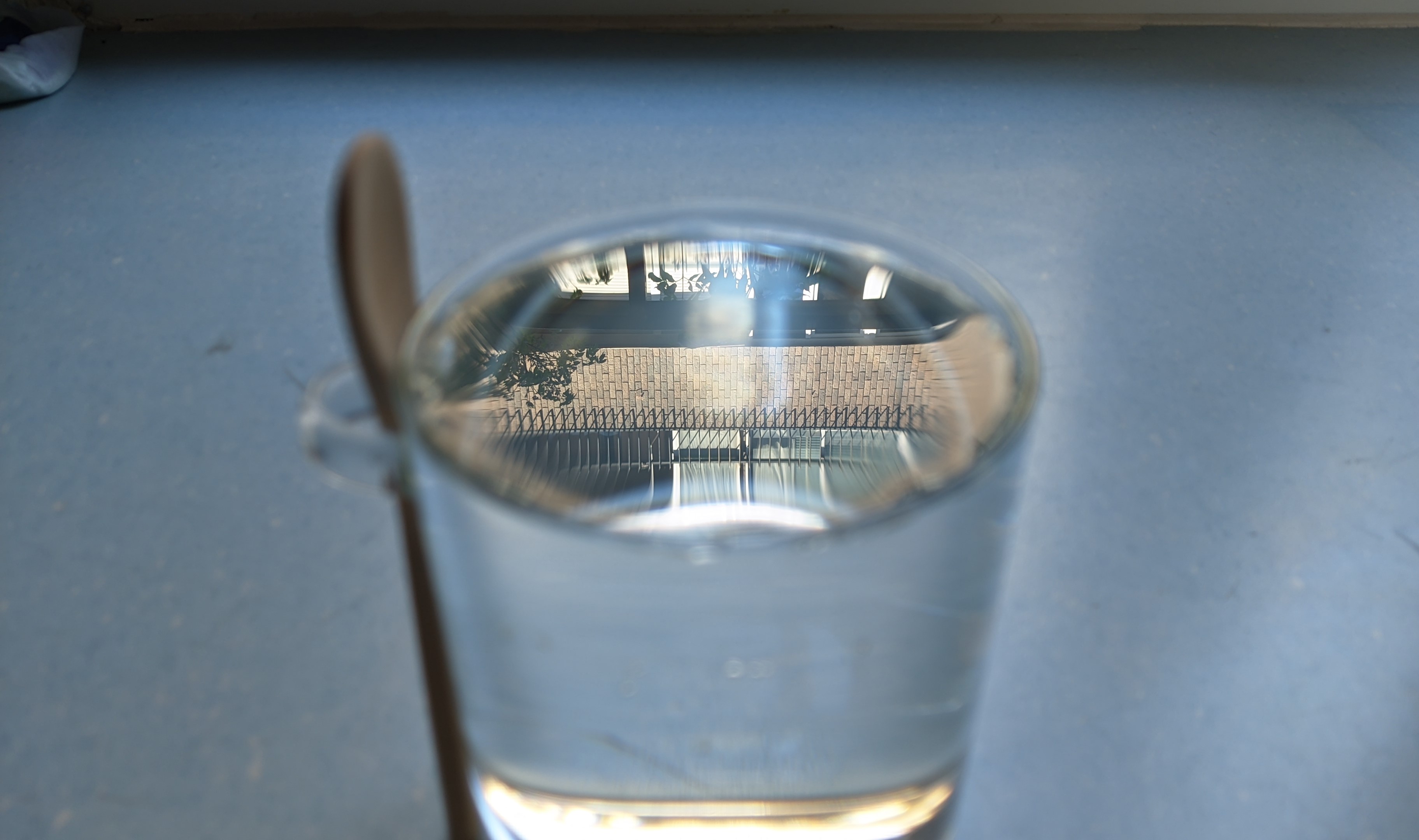 Figura 19: Como el ángulo de incidencia es considerablemente alto, por la parte de arriba la luz no puede atravesar el agua. Esto hace que podamos ver el edificio de enfrente. En el centro vemos refractado el suelo. Y, sin embargo, en la parte inferior, ¡observamos luz solar y el edificio de nuevo!